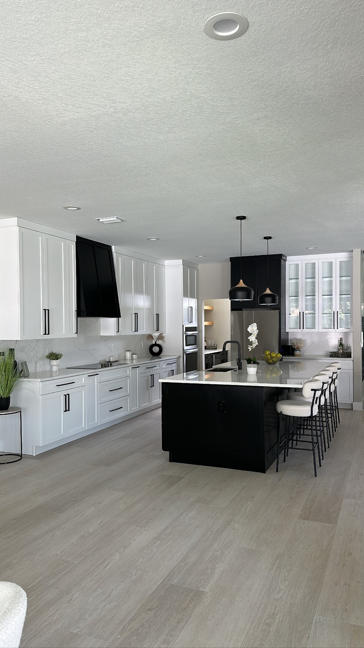 Full-height view of a finished kitchen with a black island and white custom cabinetry