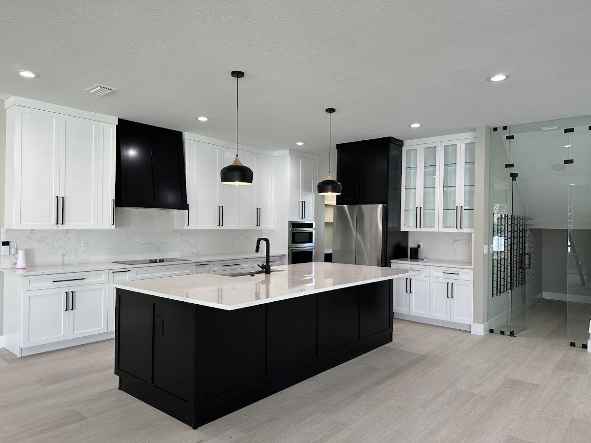 Completed kitchen with white perimeter cabinets, black island and matching range hood