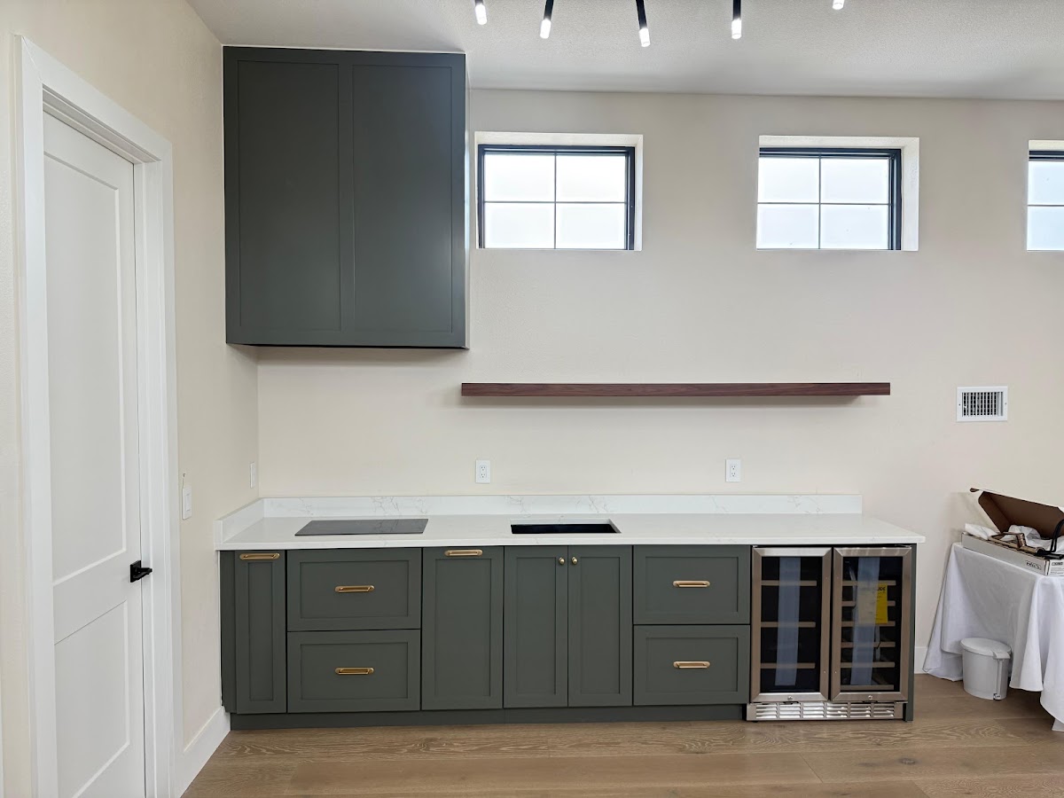 Dark cabinetry with brass-tone handles and a floating wood shelf during installation