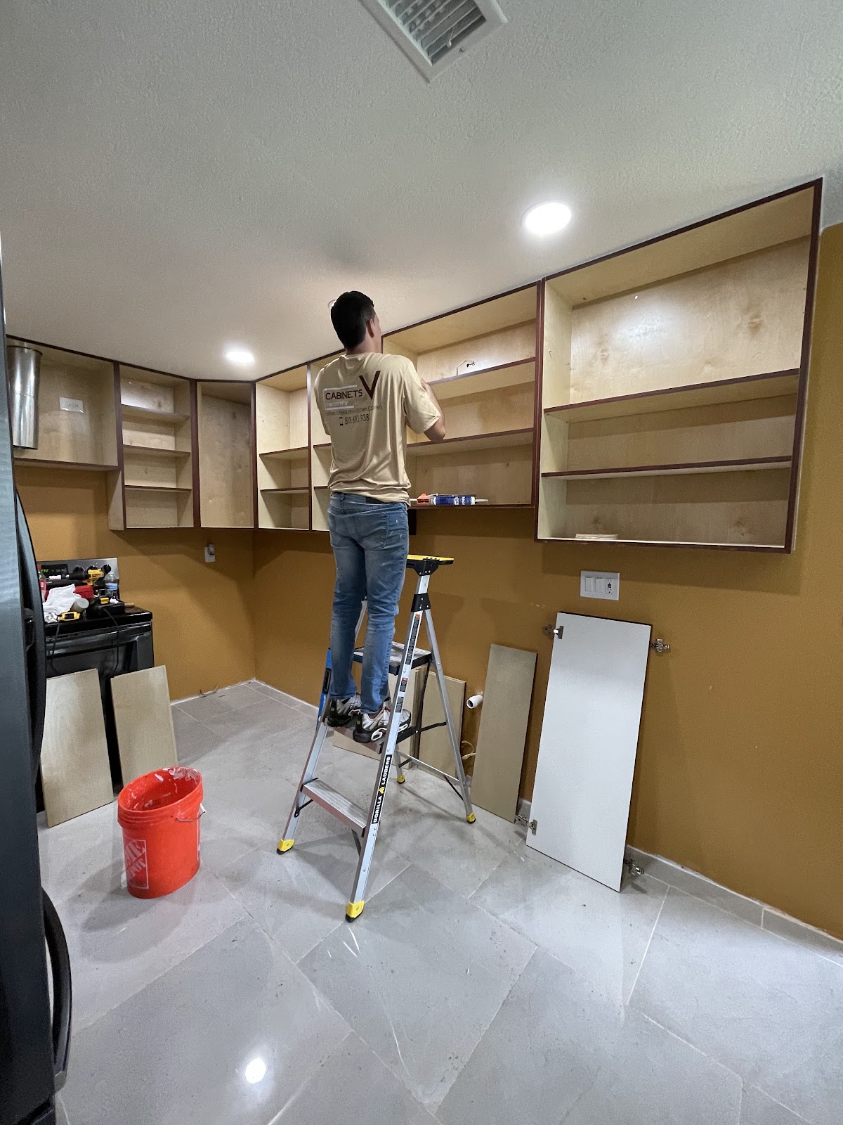 Cabinet installer fitting upper cabinet boxes during a JVCabinets20 kitchen project